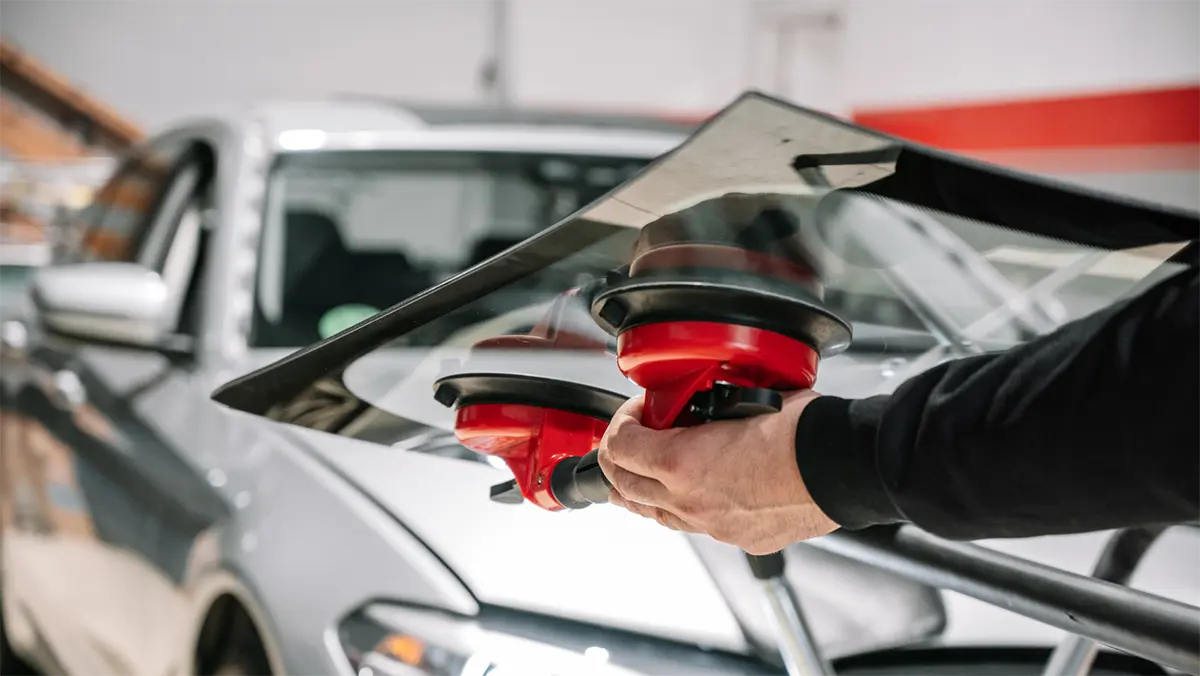 Technician fitting a new windshield with suction cup handles