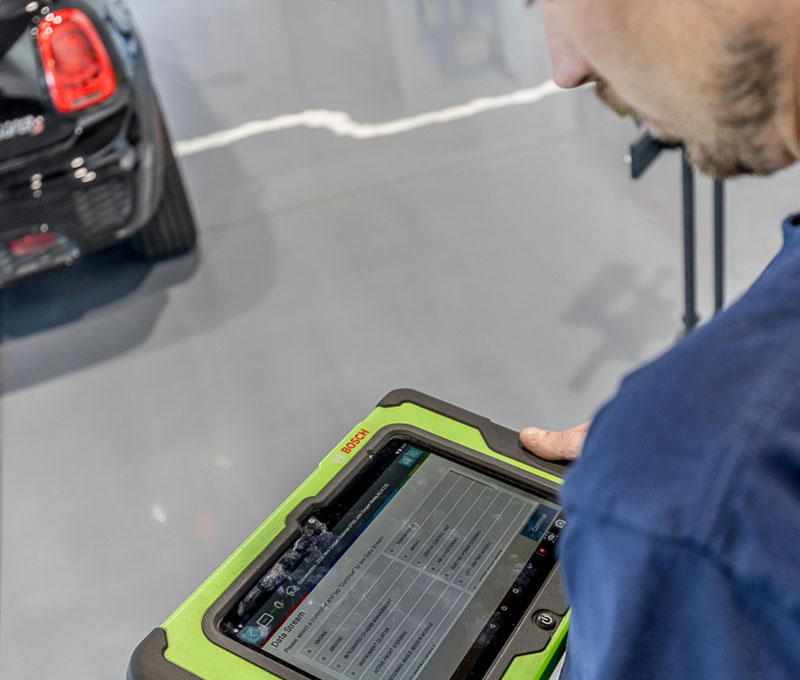 Technician using a diagnostic tablet during ADAS camera calibration